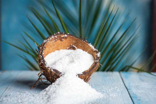 Grated coconut powder falling out of a coconut shell with copy space